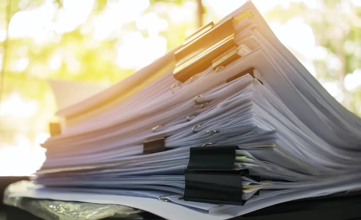 Stack of organized legal documents with gold binder clips in natural sunlight