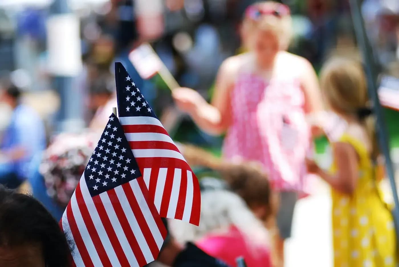 Close-up of American flag at outdoor community event with crowd in background