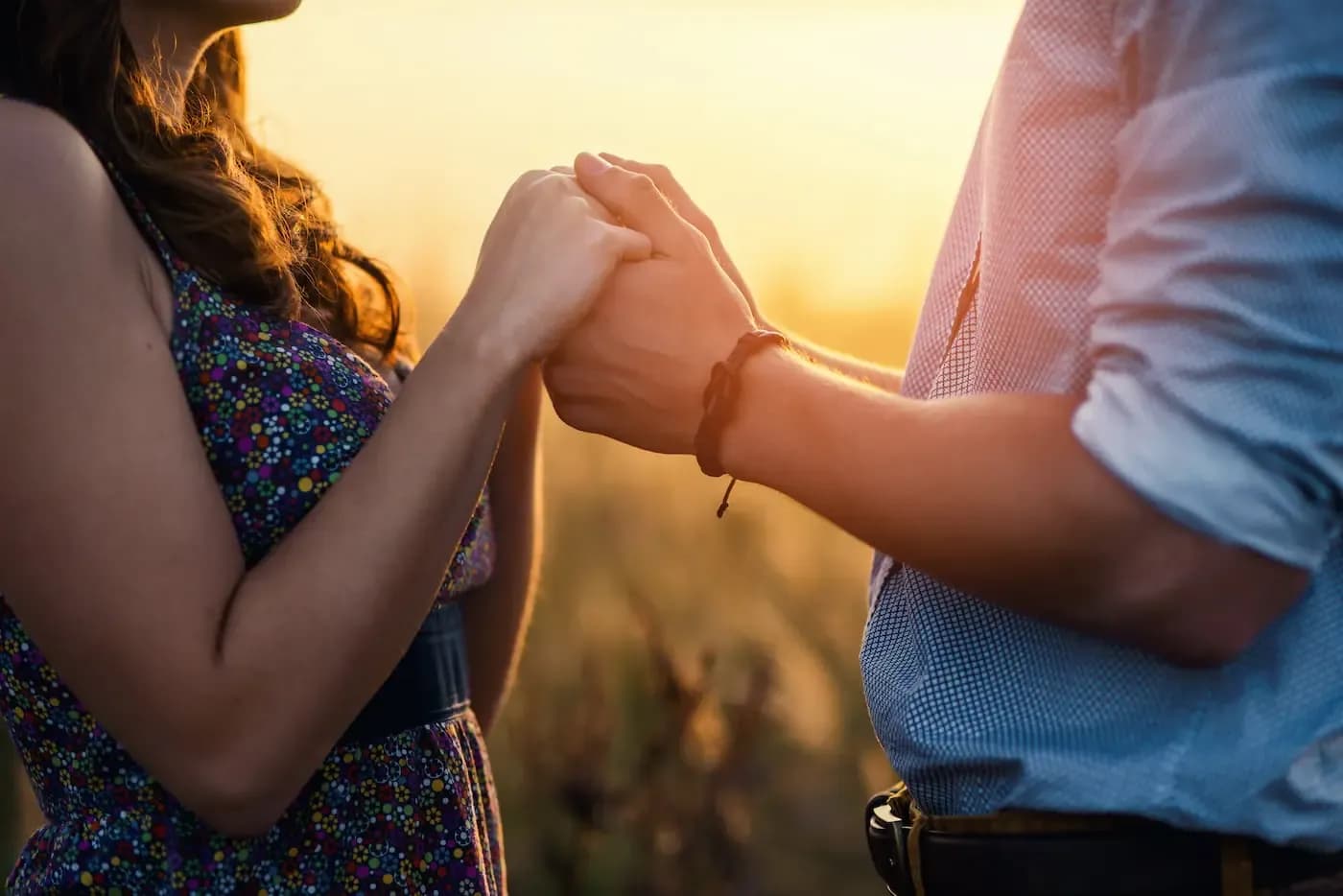 Dos niños tomados de la mano y chocando los puños frente a una puesta de sol