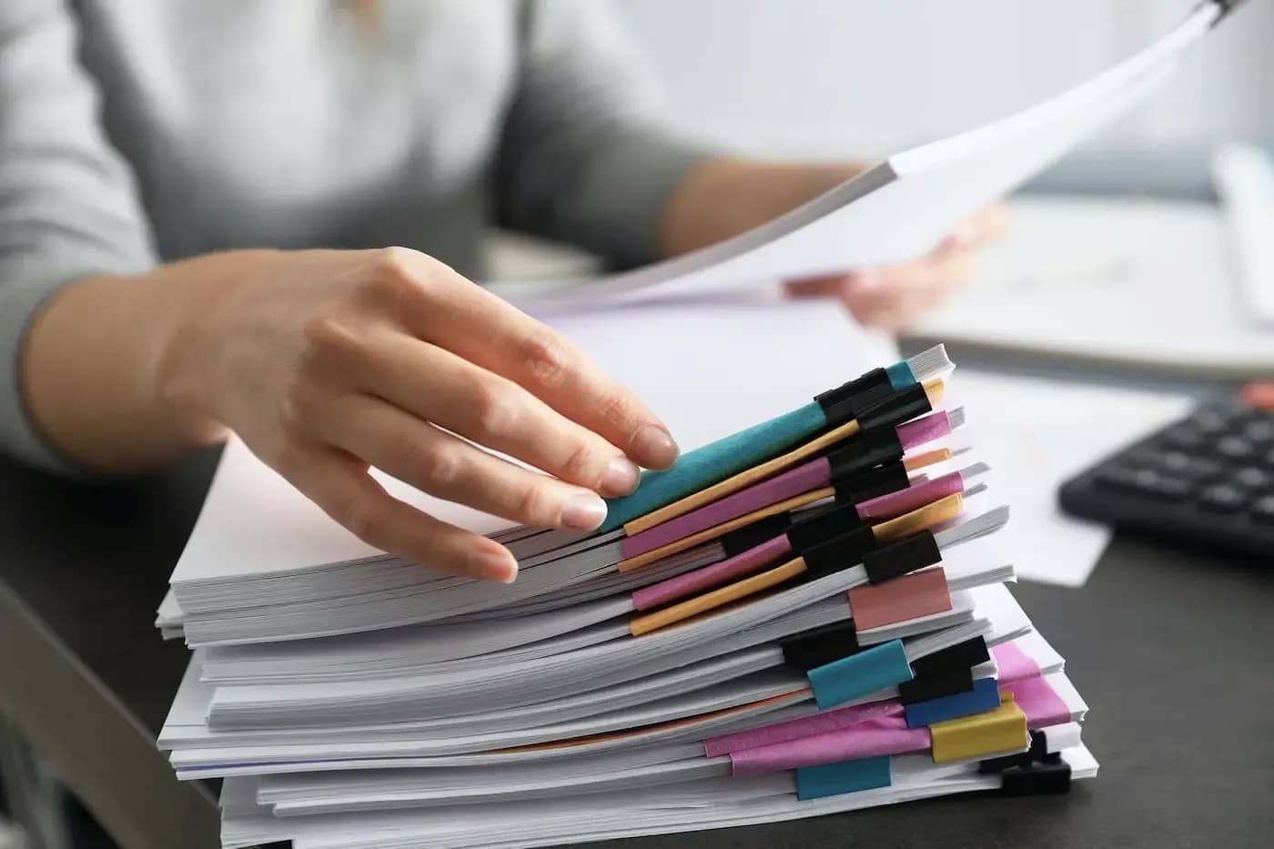 Person organizing documents with colorful file tabs at desk