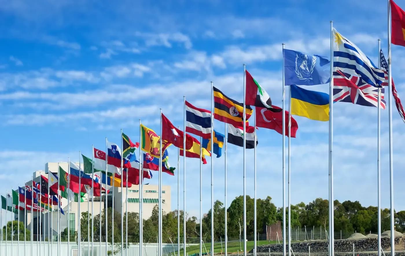 Varias banderas internacionales ondeando frente a un edificio moderno, en representación de la inmigración mundial y el derecho internacional