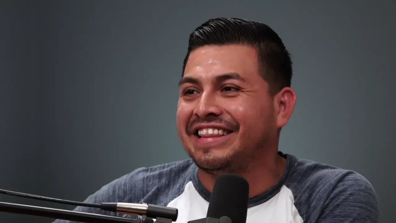 Man with microphone smiling while speaking, appears to be in professional podcast or interview setting