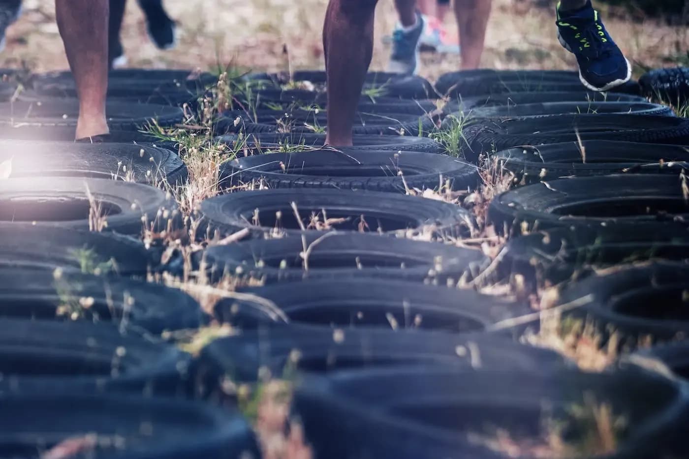 Multiple participants running through tire obstacle course during outdoor fitness training