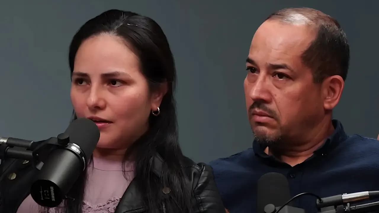 Two people speaking into microphones during a podcast recording session against a gray background