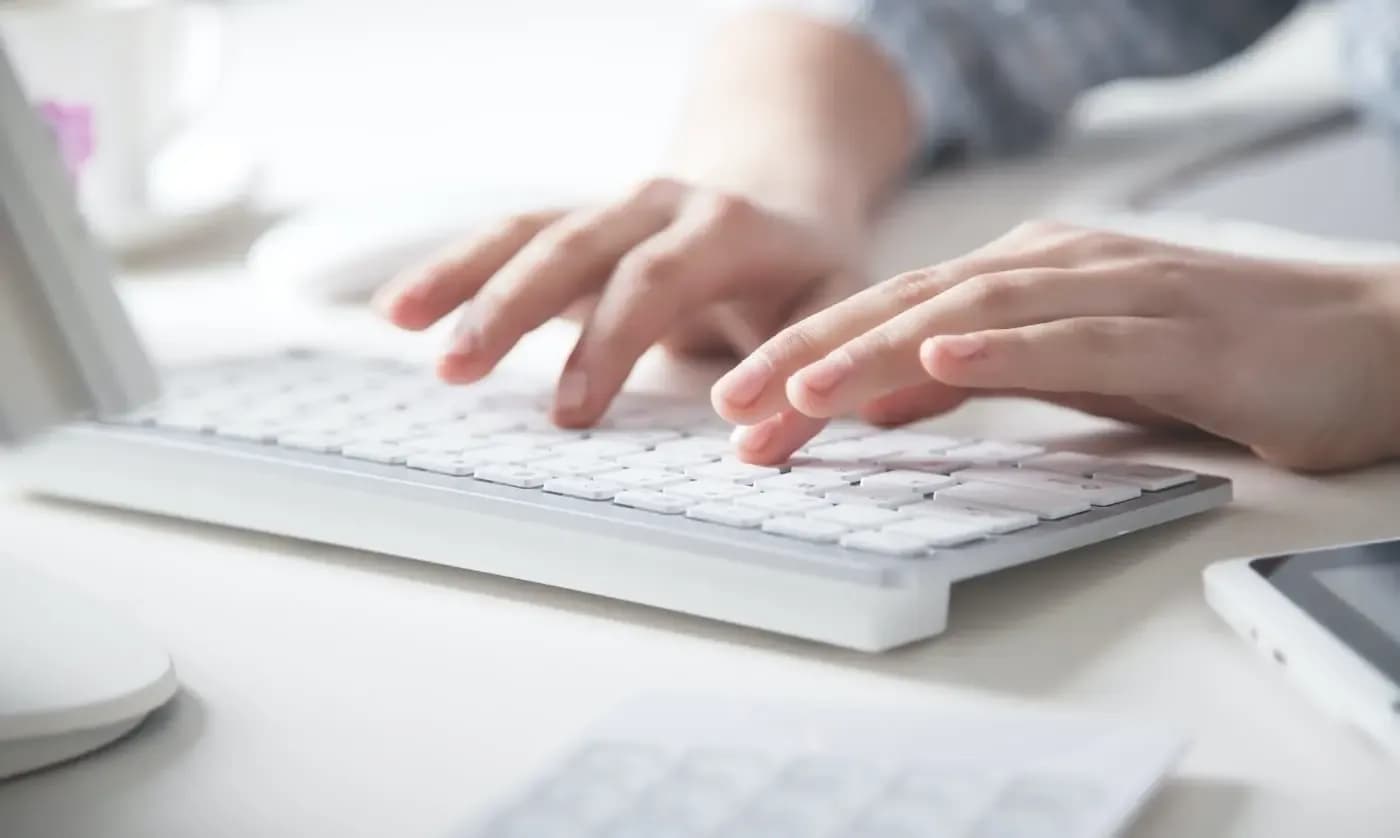 Close-up of hands typing on a white keyboard at a clean desk workspace